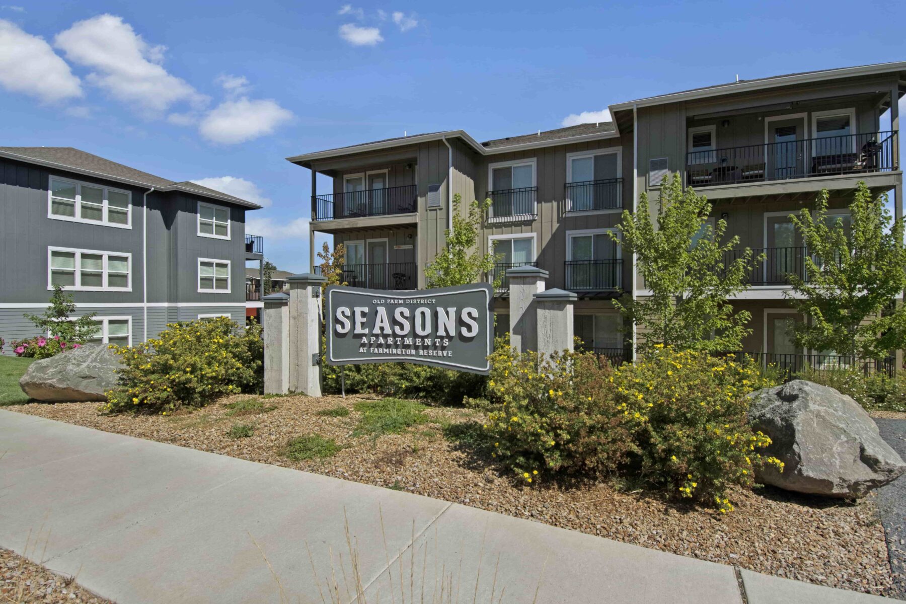 A wide shot of the property with a sign reading ‘SEASONS APARTMENTS’ in front.