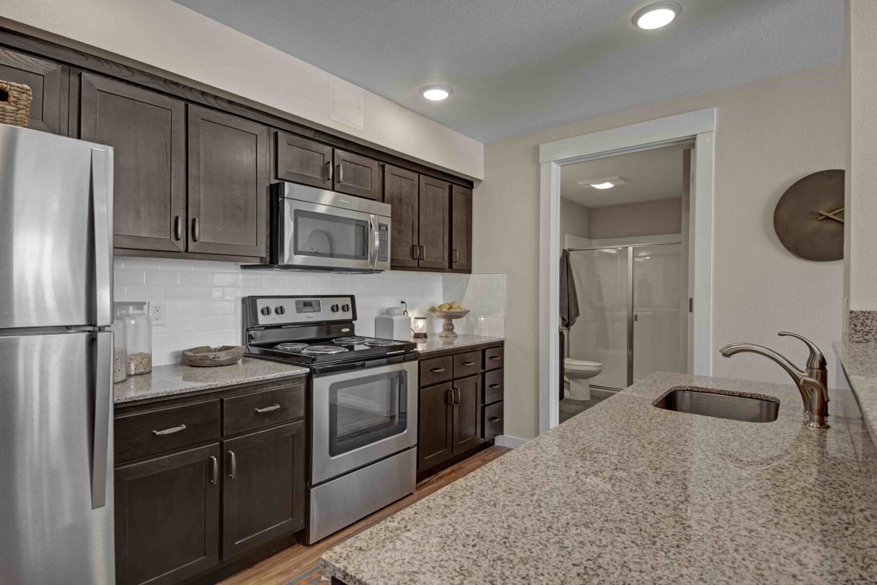 Kitchen with dark wood cabinets, stainless steel appliances, and a white tile backsplash