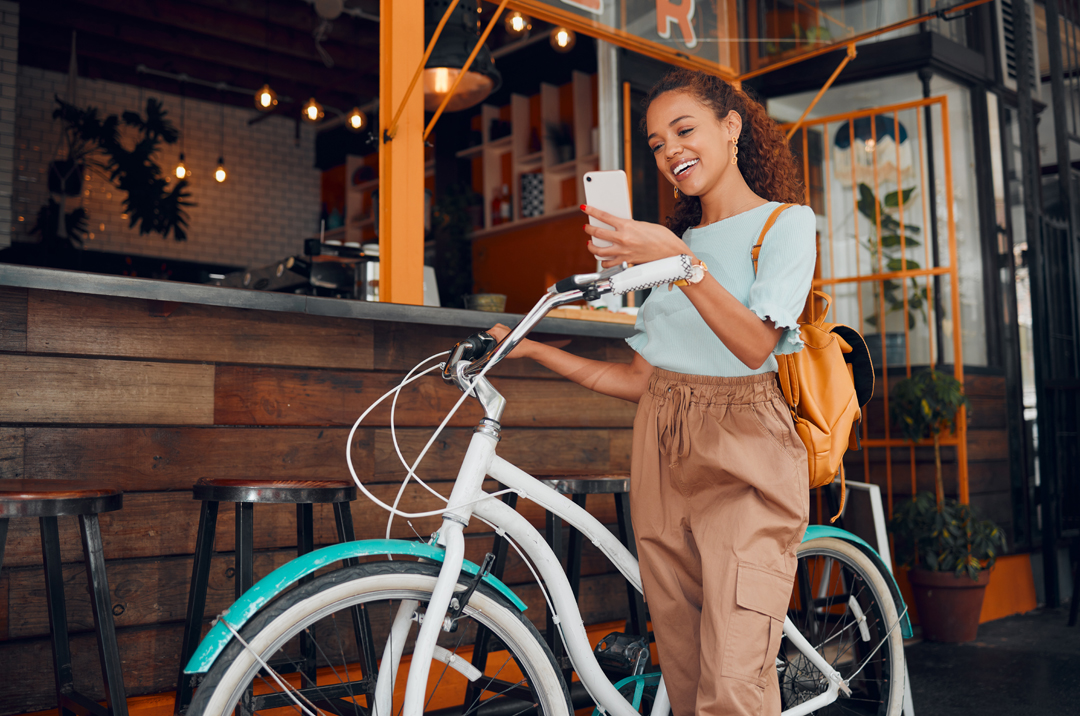 Young woman with a bicycle smiling at her phone