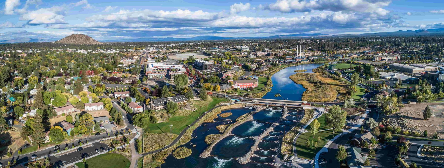 Aerial view overlooking neighborhood and surrounding area, lots of trees and a river flowing through the middle